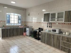 a large kitchen with wooden cabinets and a microwave at Hostel Maral in Mawāliḩ