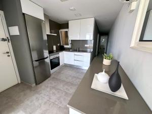 a kitchen with white cabinets and a black vase on a counter at Apartamento en primera linea con vistas al mar - VistaMar Blanes in Blanes