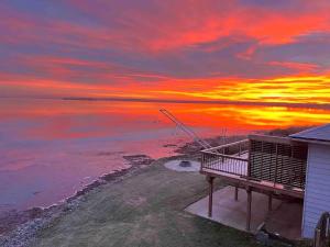 a sunset over the water with a house and the ocean at Sun Chaser Bay in Carrying Place