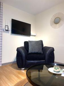 a living room with a black couch and a glass table at 12 Penn Gardens - Apart 1 in Friern Barnet +6 photos