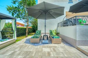 a patio with two chairs and an umbrella at Luxury Villa Nikoma with heated pool and whirlpool in Dicmo