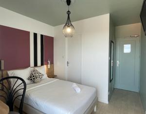 a bedroom with a white bed and a pendant light at Logis Les Cols Verts in La Tranche-sur-Mer