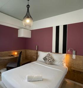 a bedroom with a white bed and a purple wall at Logis Les Cols Verts in La Tranche-sur-Mer