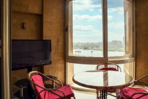 a room with a table and chairs and a large window at LuxuryApartmentDirectToTheNile in Cairo