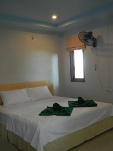 1 dormitorio con 1 cama y 2 toallas verdes en Rimlay Bungalow, en Nai Yang Beach