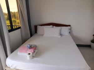 a bedroom with a white bed with a stuffed animal on it at Brent's Tourist Inn in Itaytay +6 photos