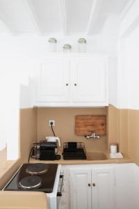 a kitchen with white cabinets and a stove top at Manto Sunset Loft in Mýkonos City