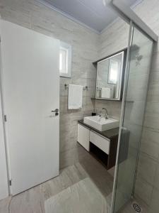 a bathroom with a sink and a shower with a mirror at Quarto acolhedor no Balneario in Florianópolis +9 photos