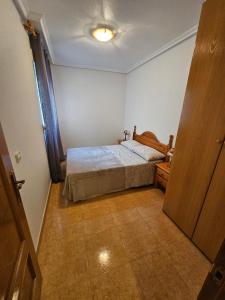 a small bedroom with a bed and a wooden door at Casa Aleks Lo Pagan in San Pedro del Pinatar