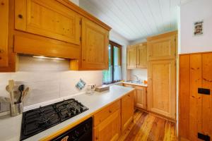 eine Küche mit Holzschränken und einem Herd mit Backofen in der Unterkunft Appartamento San Lorenzo 2 a Vinigo in Vinigo