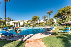 una piscina con sillas azules y palmeras en Holiday Home 'Miraflores Rancho', en La Cala de Mijas