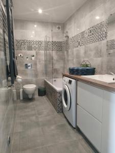 a bathroom with a toilet sink and a washing machine at Sea&Wine Apartamenty Darłówko in Darlowko +22 photos