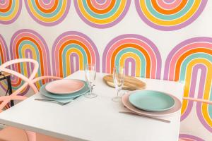 a table with plates and glasses and a colorful wall at Design et Pop avec balnéo in Lyon +12 photos