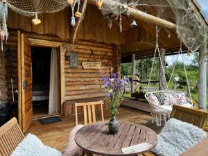 a wooden cabin with a table and flowers on the porch at Metsakuurorti puhkekeskus, Kunksmoor house in Väike-Särge +14 photos