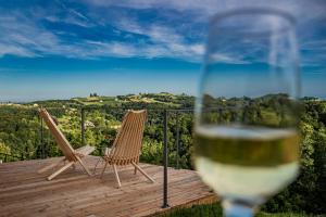 a glass of wine with two chairs on a deck at Wellness Počitniška hiša Manja in Ljutomer