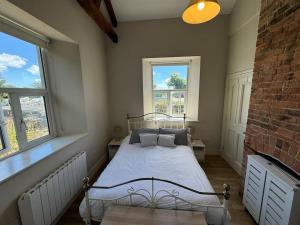 a bedroom with a white bed with two windows at Railway Cottage in Cork