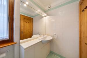 ein weißes Badezimmer mit Waschbecken und Spiegel in der Unterkunft Appartamento Michaela a Vinigo in Vinigo