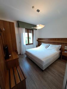 a bedroom with a large white bed and a window at Hotel Alla Dolina in Sistiana