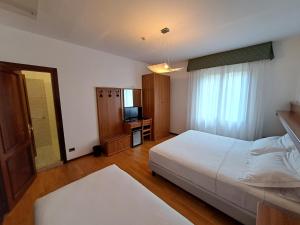 a bedroom with a white bed and a television at Hotel Alla Dolina in Sistiana