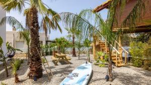 a surfboard on the beach next to a house with palm trees at D PALM Premium Living - Kalathas, Chania in Chania Town