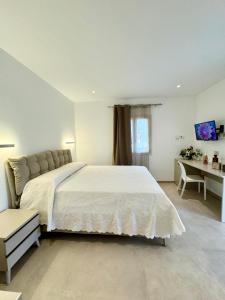 a bedroom with a large white bed and a desk at Villa Berenike in San Teodoro
