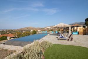 a swimming pool with blue lounge chairs at Lampetos Houses Molyvos in Mythimna