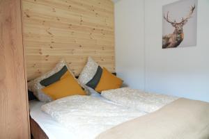 a bed with white sheets and yellow pillows at NATURAMA Glockenalm in Fischbachau