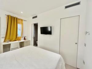 a white bedroom with a bed and a tv on the wall at Villa Berenike in San Teodoro