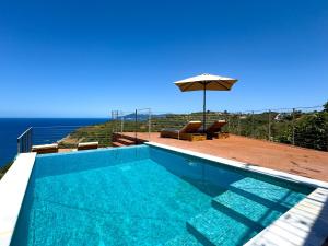 a swimming pool with an umbrella and the ocean at Captain's Villa in Skiathos