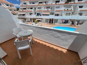 a balcony with a table and chairs and a swimming pool at Las Floritas 2 in Arona