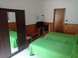 una camera con 2 letti verdi e uno specchio di Albergo Brioschi a Caponago