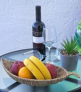 a glass table with a basket of fruit and a bottle of wine at Blue Lotus Studio in Agia Marina Nea Kydonias