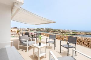 a patio with chairs and tables and a view of the ocean at Villa Enderrossall in Porto Cristo