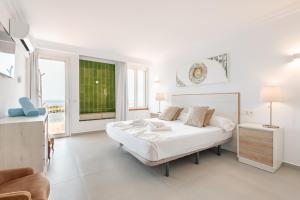 a white bedroom with a bed and a window at Villa Enderrossall in Porto Cristo +24 photos