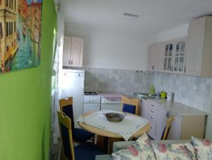 a kitchen with a table and a kitchen with green walls at Apartman Jovanovic in Sutomore