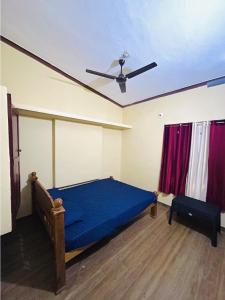 a bedroom with a blue bed and a ceiling fan at 4 Bedroom Jungle Villa in Panamaram