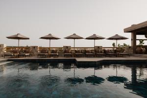 a pool with tables and chairs and umbrellas at Momi Slow Living Hotel in Hersonissos