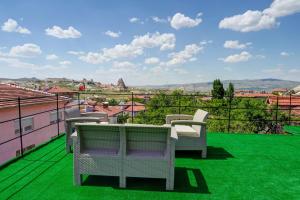 a balcony with a table and chairs on a green lawn at Nissa Cave in Göreme