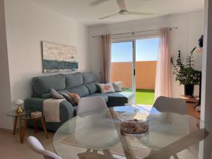 a living room with a blue couch and a glass table at OBSIDIAN Aguamarina in Puertito de Güímar