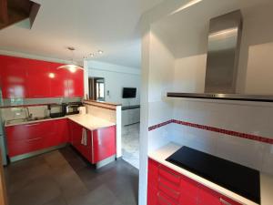 a red and white kitchen with red cabinets and a sink at Chez Maison Grande in Aosta