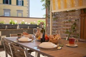 a wooden table with food and a bottle of wine at Dimora Altemura in Lucca
