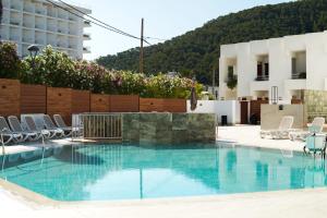Una piscina con sillas y un edificio. en Typic Oasis Sa Tanca, en Cala Llonga