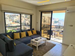 a living room with a blue couch and a table at Dair Ghbar Gate Apartments in Amman