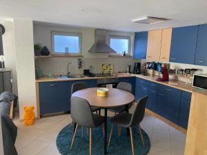 a kitchen with blue cabinets and a table and chairs at House Apartment am See in Markkleeberg