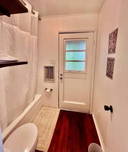 a bathroom with a toilet and a window and a door at Cabin Nestled on Skiers Cove South Toledo Bend Lake 3 bedroom-5 beds in South Toledo Bend