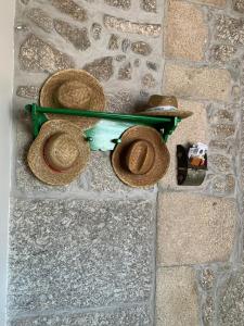 a green bench with hats on it on a sidewalk at Casa das Fontes in Ponte da Barca