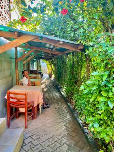 a woman sitting at a table under a pergola at Safari Homes in Kampala