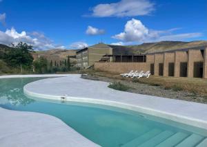 a swimming pool with white chairs and a building at Balneario de la Albotea in Cervera del Río Alhama