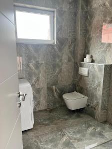 Un baño con inodoro y ventana. en Villa Holiday, en Bihać 6 fotos más
