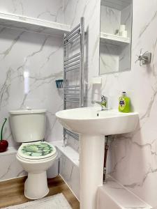 a white bathroom with a toilet and a sink at Westfield Gardens - 3 Bedroom Apartment in Goodmayes